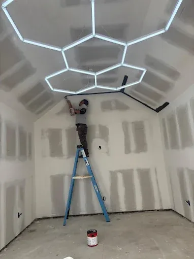 Worker installing LED lighting during a garage remodeling project by Portillo's Carpentry Demolition Corp